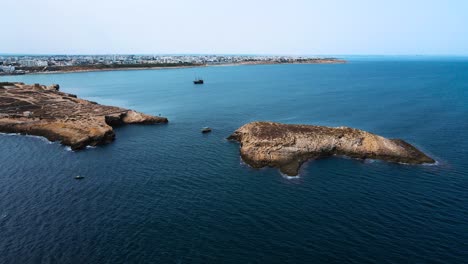 a beautiful ocean scene with blue water and rocks in the background. there is a boat out in the water on the left side of the image.