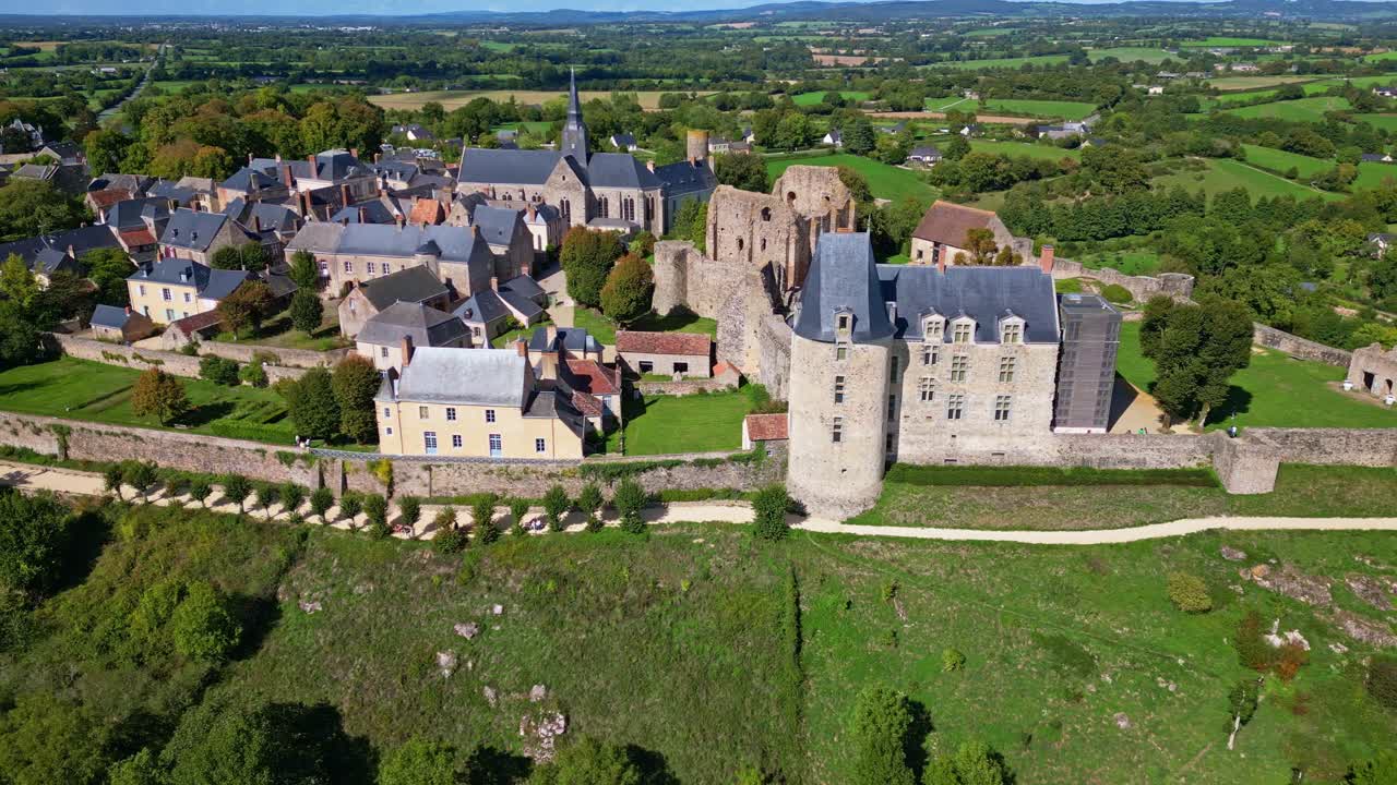 Drone shot panning from right to left over the medieval city of Sainte-Suzanne in Mayenne, showing the castle, ramparts and surrounding countryside