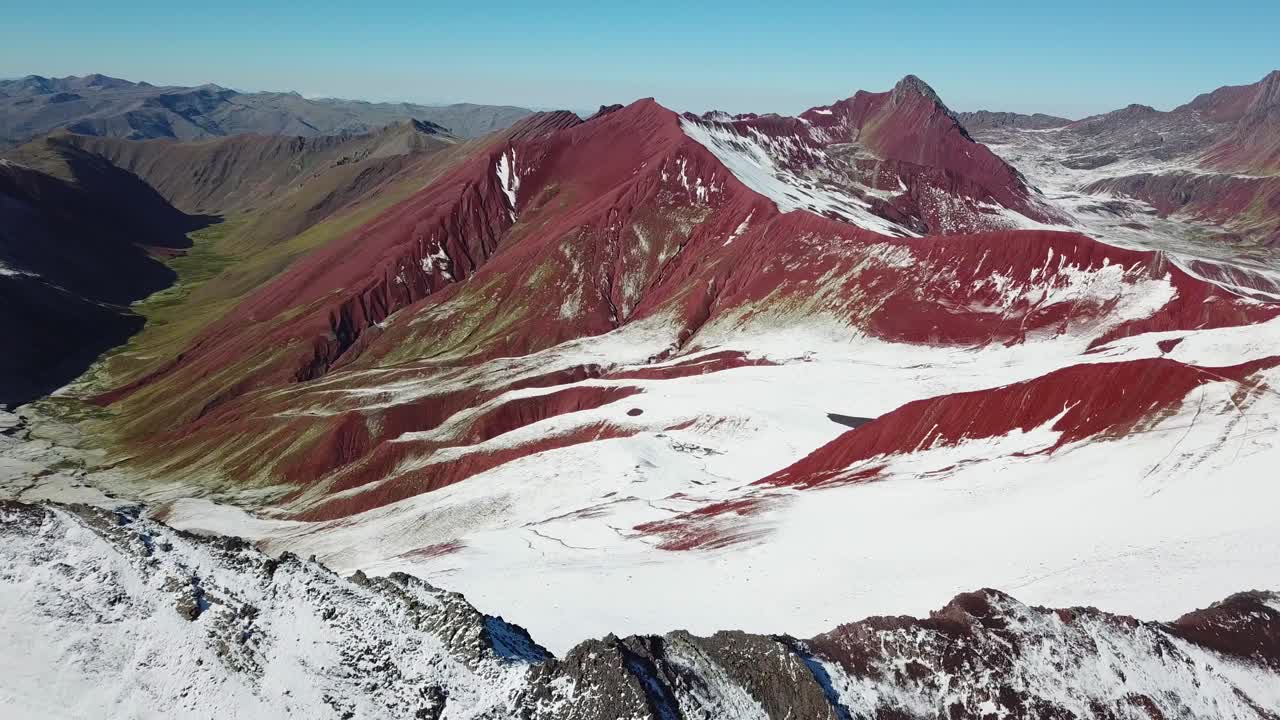 Aerial, drone shot over snowy ground, towards red mountains, near the Vinicunca, rainbow mountain, sunny day, in Pitumarca, Andes, Peru, South America