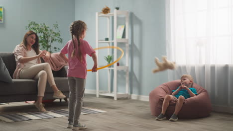 young woman, mother with children playing in room, throwing toys