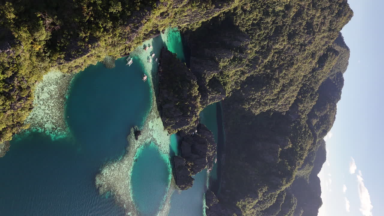 Drone view of Philippines, Coron Island’s untouched coastline, surrounded by lush forests and clear waters. Aerial view of bungalows and lagoon. Slow rotating shot. Vertical video.