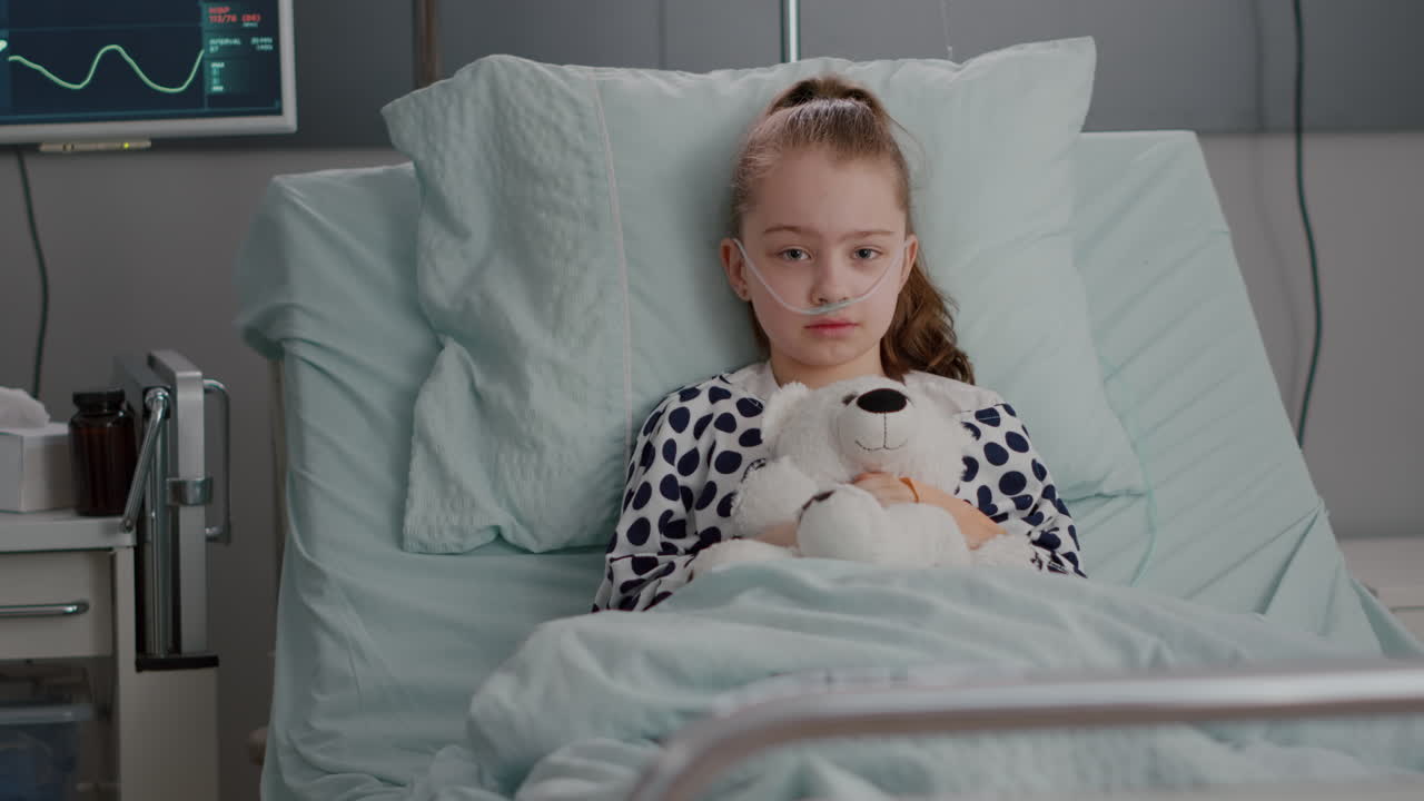 Portrait of lonely little child looking into camera holding teedy bear in hands