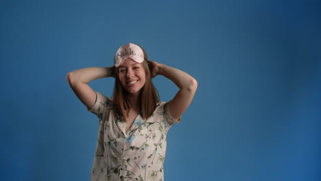 woman in pajamas wearing a sleep mask and stretching