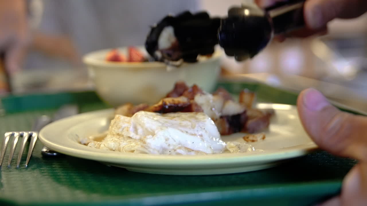 A man serves himself potatoes with his over-easy eggs at a cafeteria.
