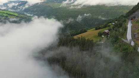 Vista-Aérea-De-Nubes-Sobre-Un-Bosque-Y-Un-Camino-De-Montaña-Sinuoso,-Capturando-La-Belleza-Natural-Y-El-Paisaje-Sereno.