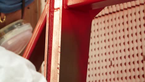 woman covering with red paint surface of metal billet. hand holding spray gun