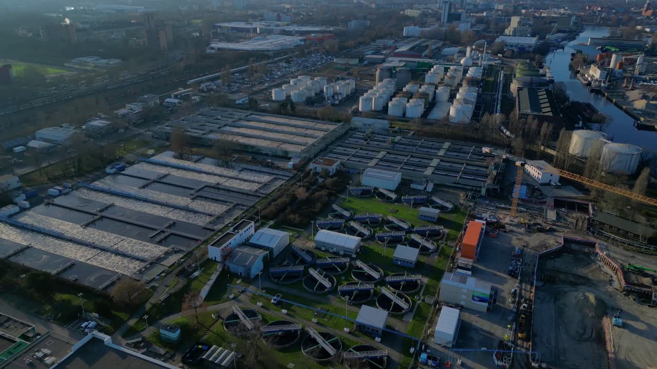 Berlin biogas plant with its large white tanks reflecting on the river next to it during sunset. Spectacular aerial view flight speed ramp hyper motion time lapse