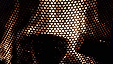 closeup logs on flames inside metallic perforated round bin. winter bonfire,