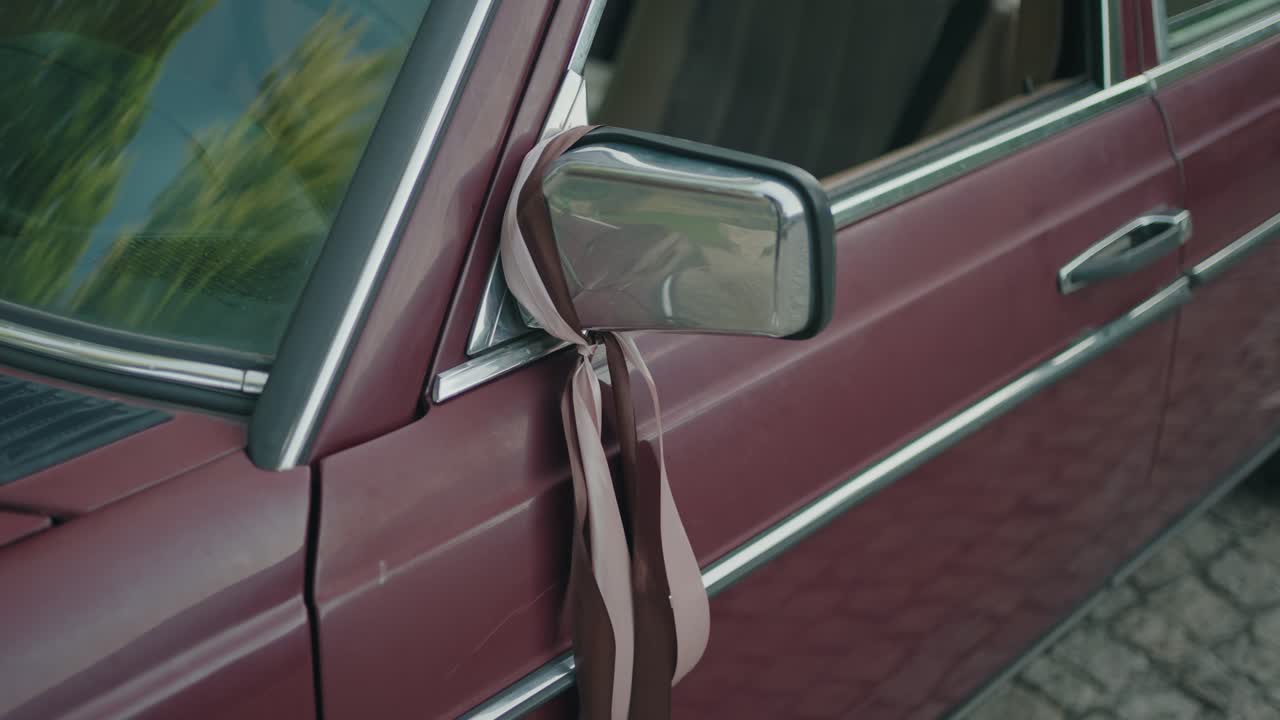 Old red car decorated with ribbon on side mirror