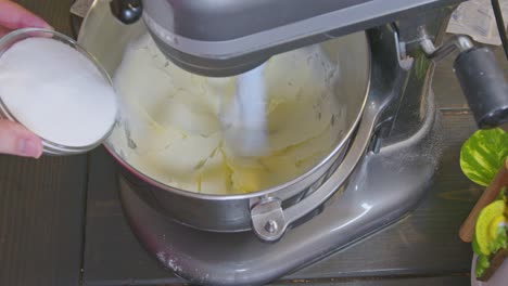 adding sugar to butter that’s been creamed while the mixer is still mixing