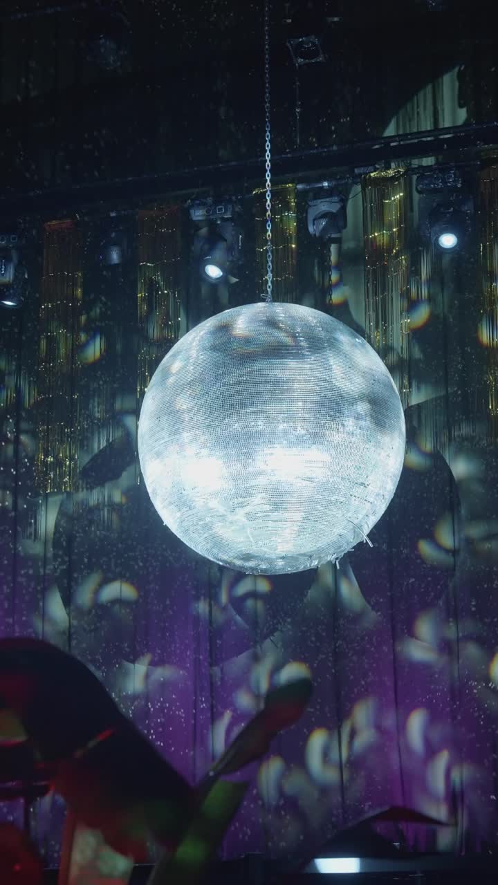Vertikale Aufnahme einer Discokugel, die Lichter in einem dunklen Innenraum reflektiert