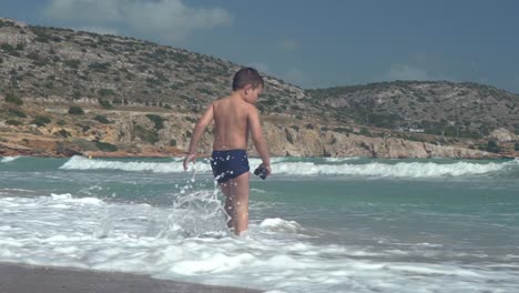 slow motion shot of caucasian boy toddler, enjoying the sea, at beach of varkiza, greece