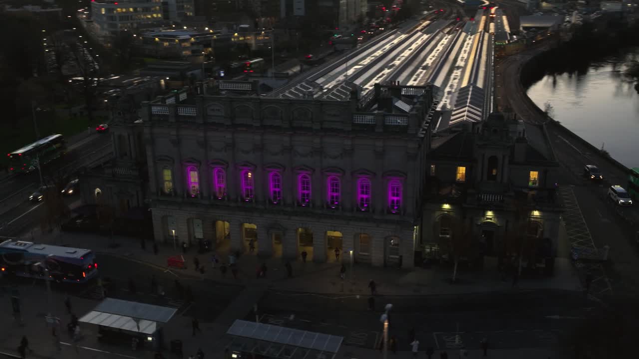 4K cinematic drone footage of Heuston Station in Dublin at sunset, highlighting the historic building, approaching trains, and the Dublin skyline under dramatic sunset hues. Dublin_0010