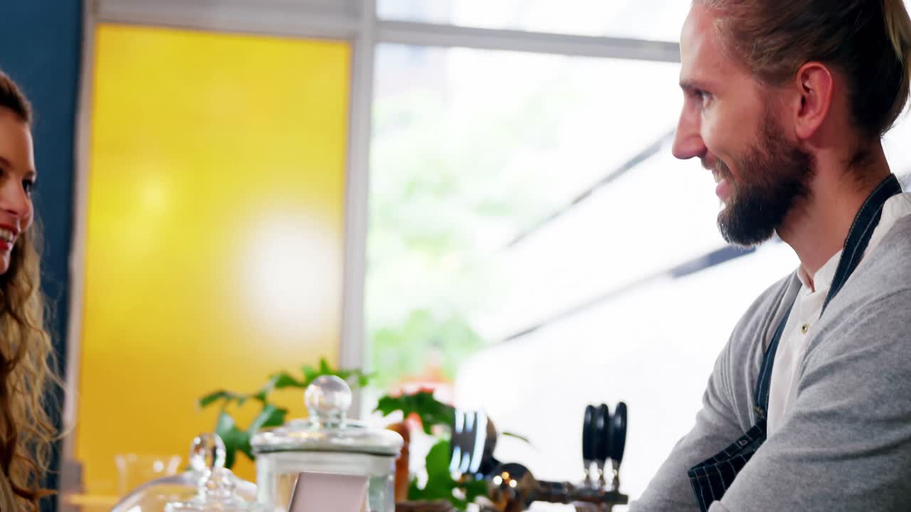 Waiter serving coffee to female costumer at counter