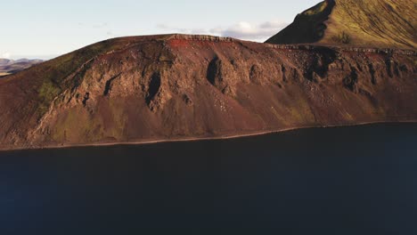 Aerial:-Blahylur-Crater-Lake-has-placid,-crystal-clear-waters-surrounded-by-mountains