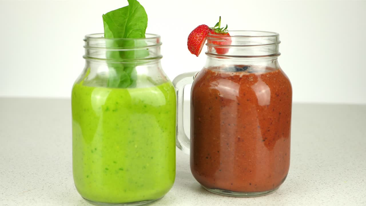 Tracking shot of two appetizing smoothies, presented in novel mason jars