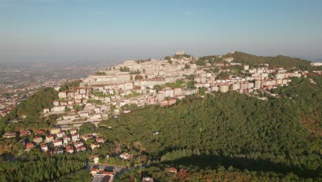 San-Marino,-Monte-Titano,-drone-view-of-the-sun-side-of-the-mountain,-4K