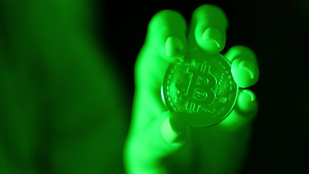 Close up hand holding Bitcoin in green light symbolizing crypto economy and risk