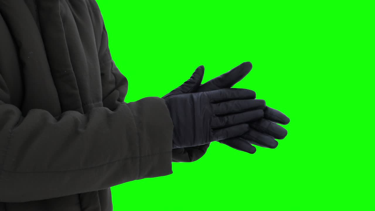 Warming hands in gloves in cold weather against green screen