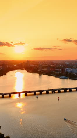 Stunning view of Boston at golden hour. Cityscape lit with orange light of setting sun. Orange sky reflecting in the river. Top view.. Vertical video