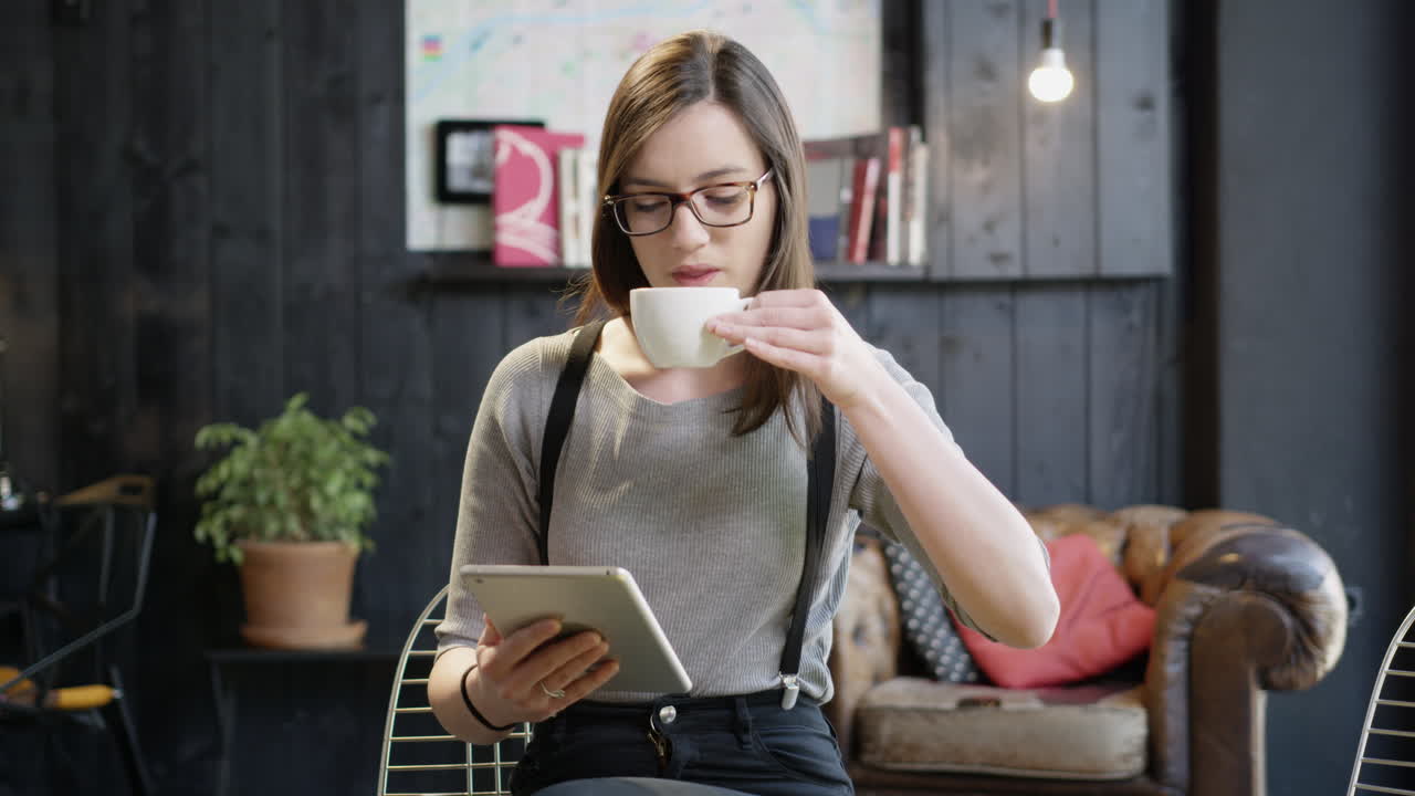 mujer usando tableta y bebiendo café