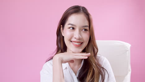 쾌활한 예쁜 소녀가 앉아서 실내에서 카메라를 보고 웃고 있습니다.