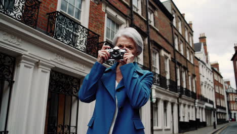 elderly woman with vintage camera on city street