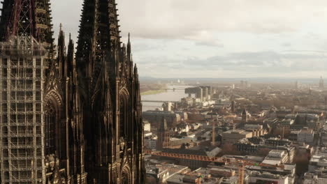 Aerial-cinematic-shot-of-two-old-gothic-towers-of-Cologne-Cathedral.-Revealing-Rhine-river-flowing-around.-Cologne,-Germany