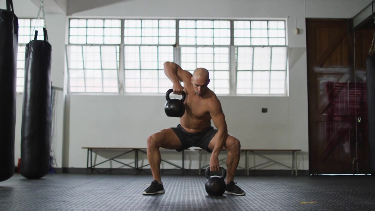 Allenatore uomo che esegue sollevamenti con kettlebell in palestra mentre un'interfaccia utente social si muove, oscurando il soggetto