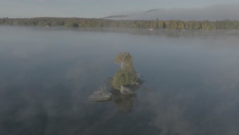 lone island surrounded by light mist orbiting aerial shot