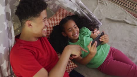 Happy-biracial-father-and-daughter-using-smartphone-together