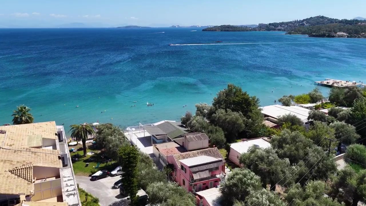 Vista aérea de drone do resort de praia de Dassia em Corfu, Grécia, com hotéis com piscina e mar azul.