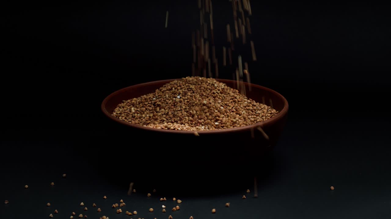 Hands Scooping and Pouring Buckwheat Groats into a Bowl