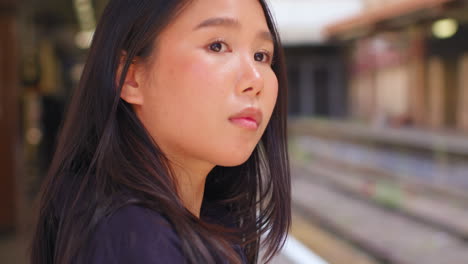 Close-Up-Of-Young-Woman-Waiting-On-Railway-Station-Platform-For-Train