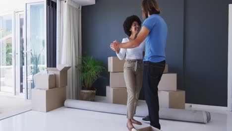 Paar-Gemischter-Rassen-Tanzt-Gemeinsam-Zwischen-Pappkartons-In-Einem-Neuen-Apartmenthaus