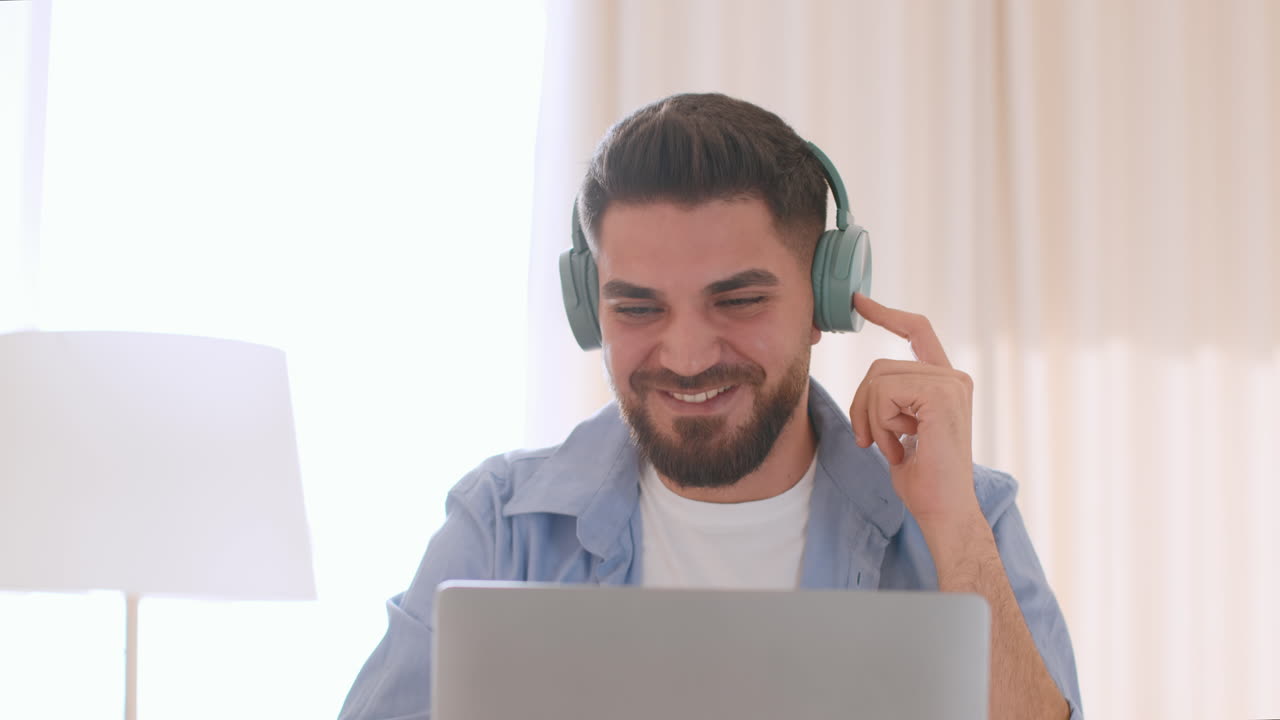 Young Man Smiling with Headphones While Using Laptop