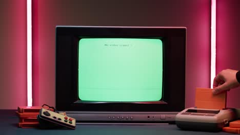 old television with blue screen on red neon background. close-up of vintage tv and retro playstation, changing cartridges. antique video game, nostalgia