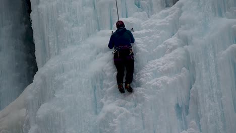 close up of woman ice climbing on frozen water fall