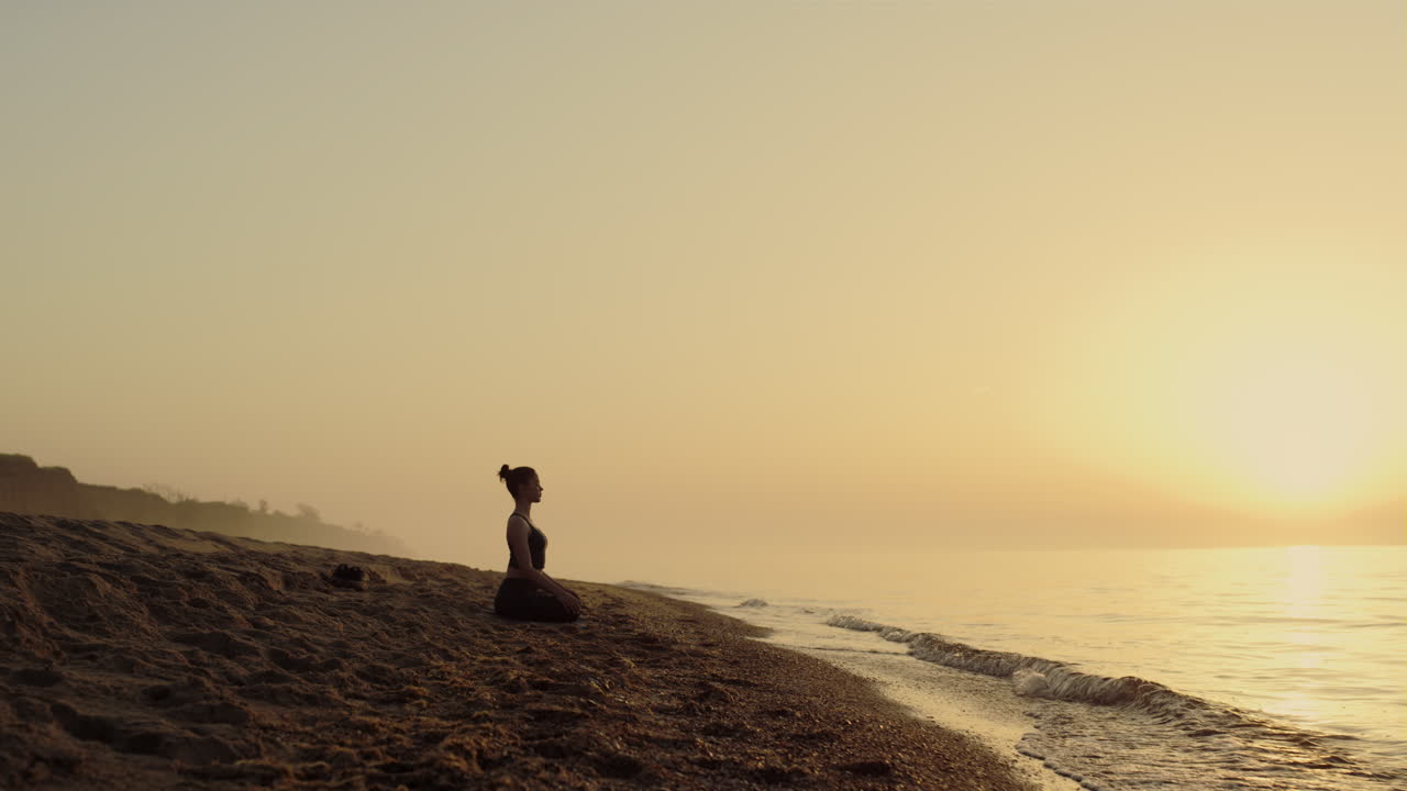 mujer enfocada practicando meditación en la playa. mujer de yoga sentada en la postura del loto.