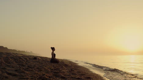 focused woman practicing meditation on beach. yoga woman sitting lotus pose.