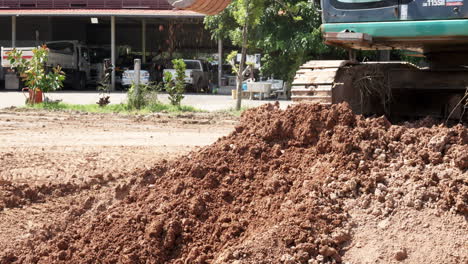 gathering and scooping excess soil using a backhoe excavator to level the field for a construction area.