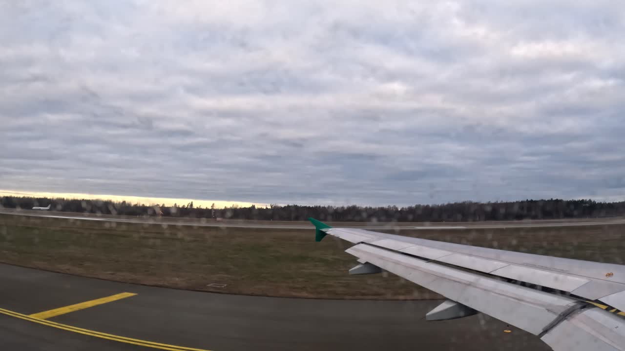 Aircraft taxiing on tarmac, view through window with visible wing