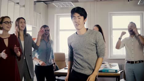 happy asian young businessman dancing at casual office party. japanese employee celebrates victory with colleagues 4k