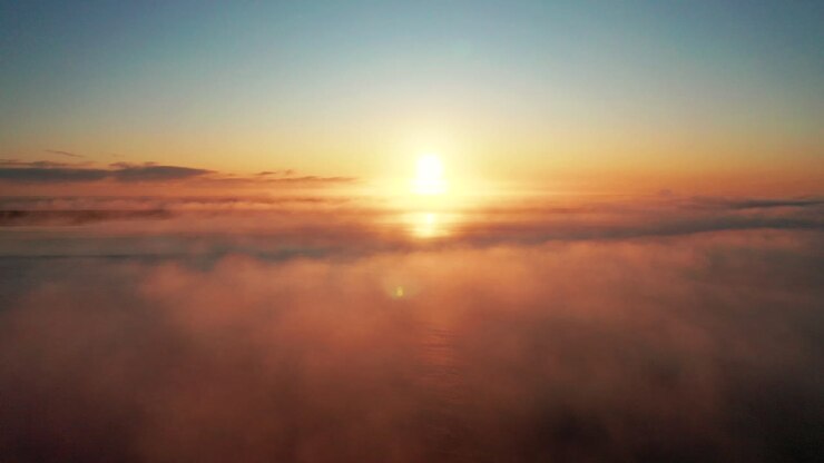 Nuvole che si muovono sopra il mare con un tramonto sullo sfondo nell'Islanda del Sud - Riprese aeree con drone