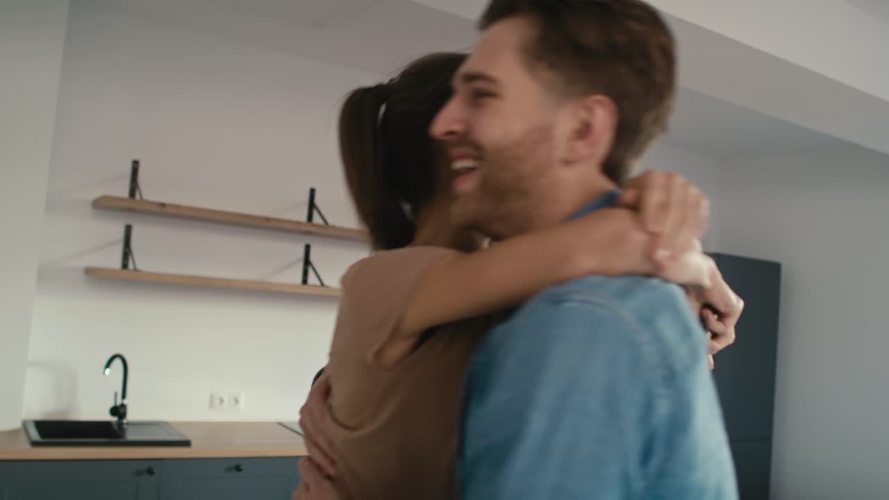 una pareja caucásica muy emocionada debido a su nueva casa y abrazándose en su nuevo apartamento.
