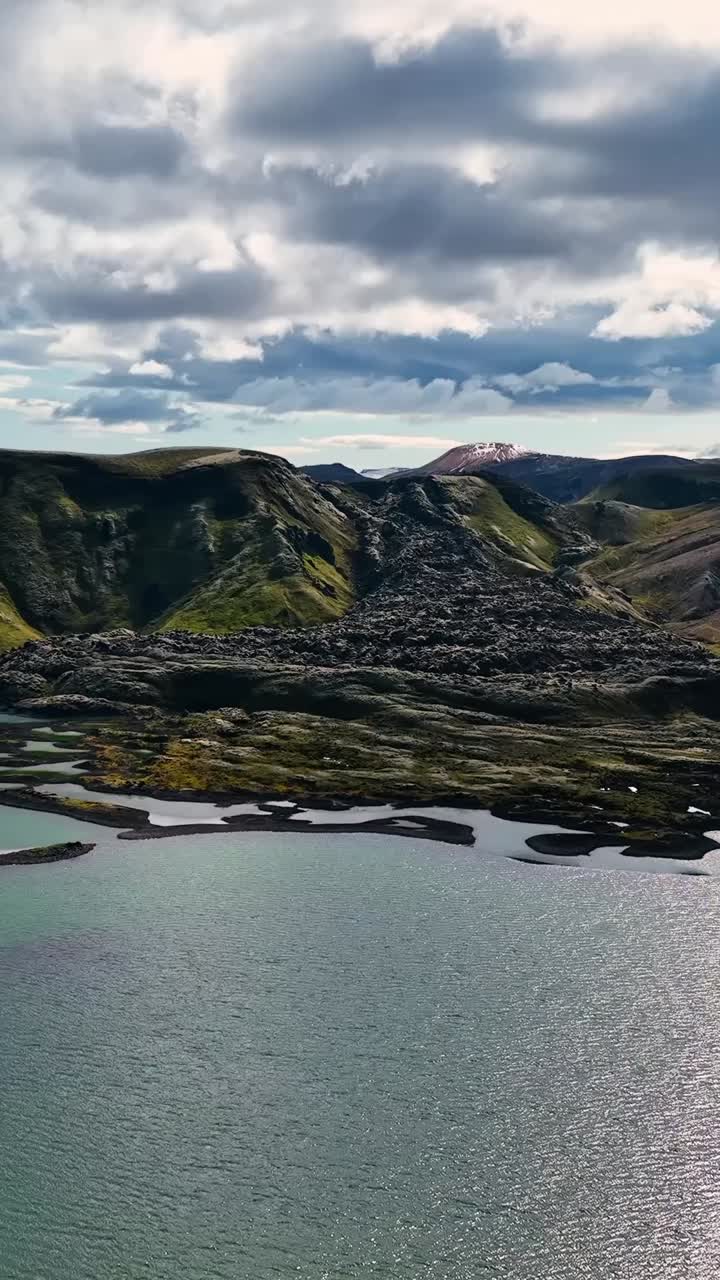 Aerial view over Iceland’s highlands green lake with mountains with snow