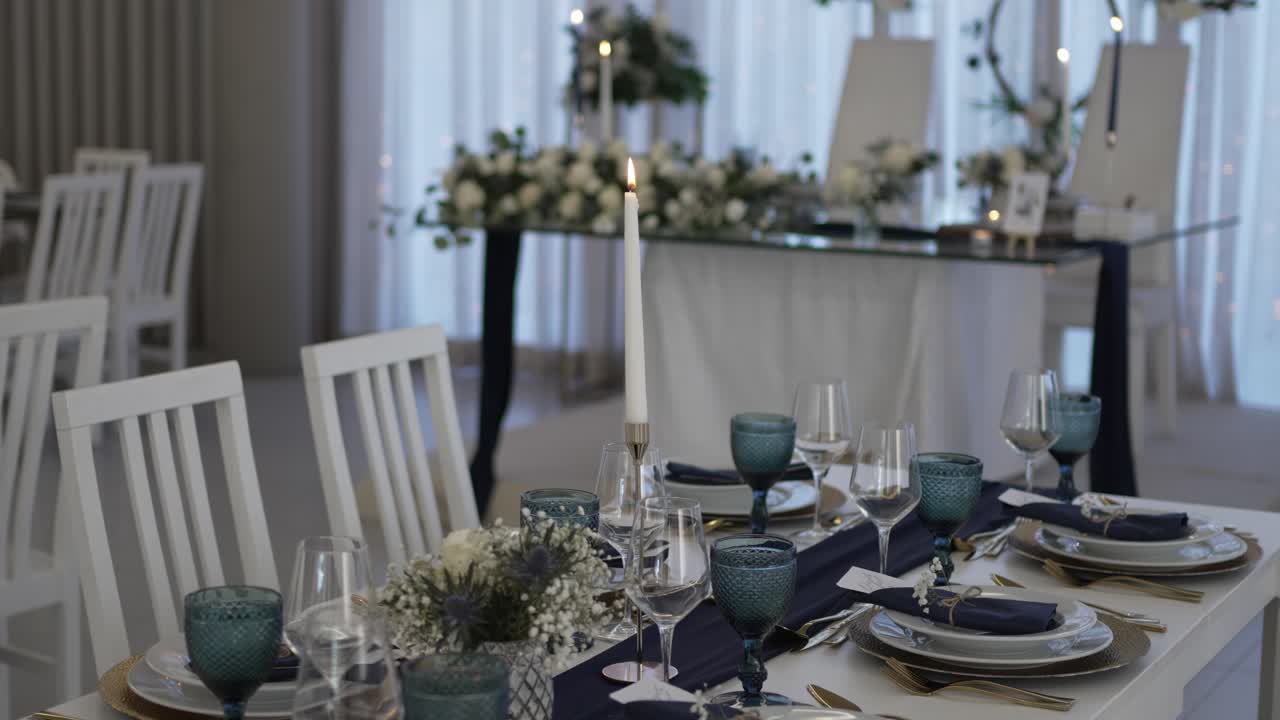 Elegant wedding table setup with blue glassware, candles, and floral decor