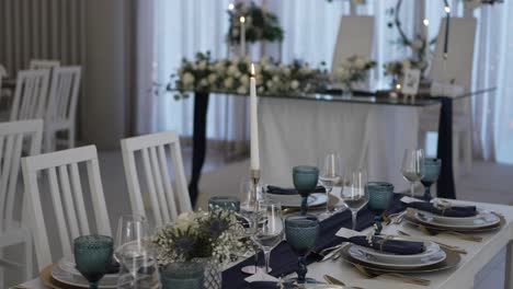 elegant wedding table setup with blue glassware, candles, and floral decor