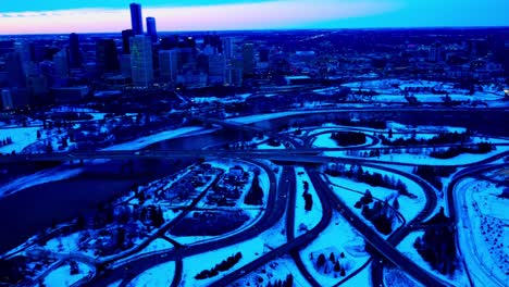 winter aerial drone fly out from downtown edmonton north east side to the south east side crossing the north saskatchewan river reflective shadowed bridges spiral multi layered overpasses into bridges