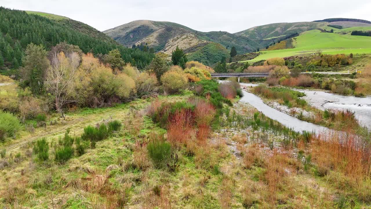 Aerial view of a serene river winding through lush greenery and hills at Lake Tekapo, captured in natural daylight